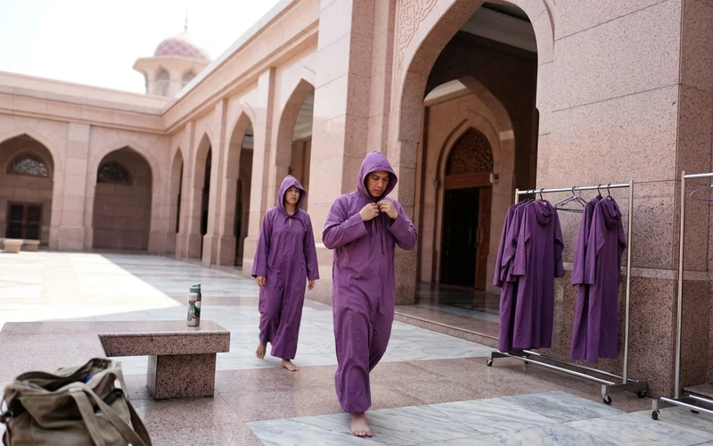 Visitors in free loaned robes walking across the Putra Mosque courtyard