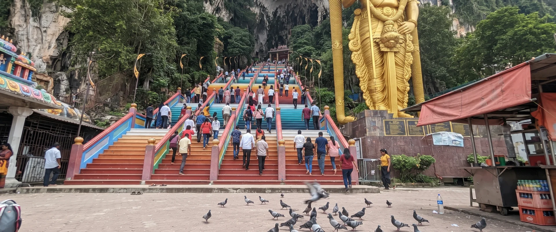 The Batu Caves staircase and Lord Murugan statue photographed from the base on a bright morning
