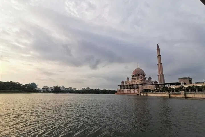 The Putra Mosque and its minaret seen from the water under an overcast sky